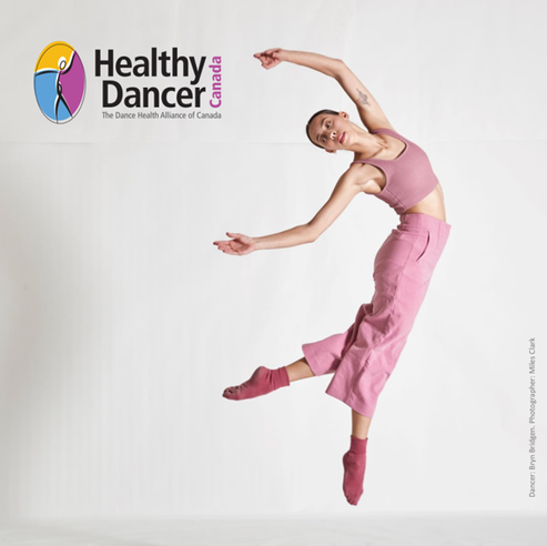 A dancer, dressed in a dark pink tank top and pants, jumping in the air